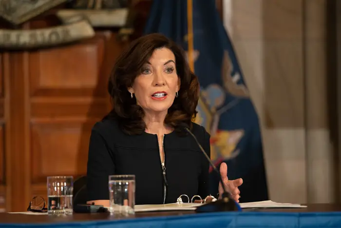 Governor Hochul, wearing a black jacket, is sitting at a table in the executive chambers